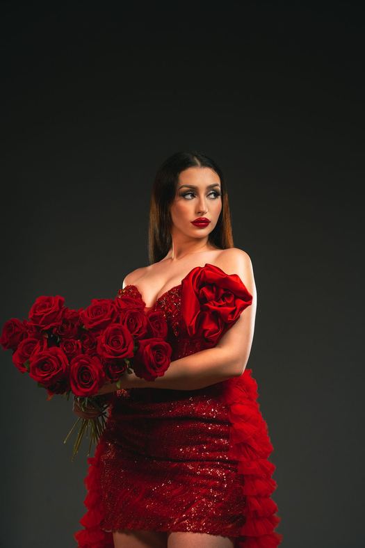 Enchantress — Red sequin with an oversized satin rose at one shoulder and ruffles sweeping out below it.